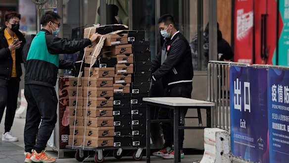 Workers push a cart loaded with Nike shoes past a security post at a shopping mall in Beijing last week.