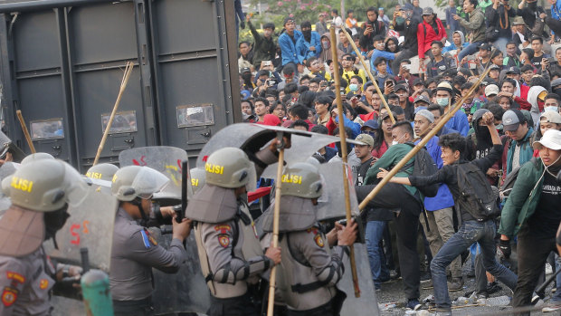 Student protesters throw projectiles at riot police outside the parliament building in Jakarta, Indonesia, on Tuesday.