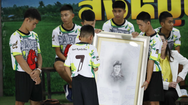Coach Ekkapol Janthawong, left, and some of the 12 boys paid tribute to a slain diver after their rescue.