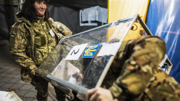 Ukrainian government soldiers, members of the local election commission, open a ballot box in a tent using as a polling station.