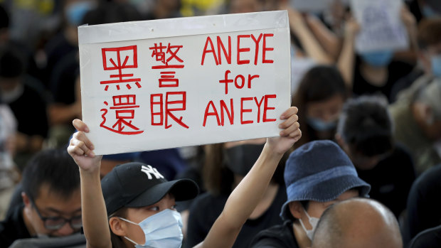 A woman protests police violence with a placard that reads "Black police, Return eye," during a sit-in at the Hong Kong International Airport arrivals hall.