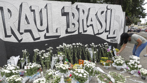 A woman leaves flowers one day after a mass, school shooting outside the Raul Brasil state school in Suzano.