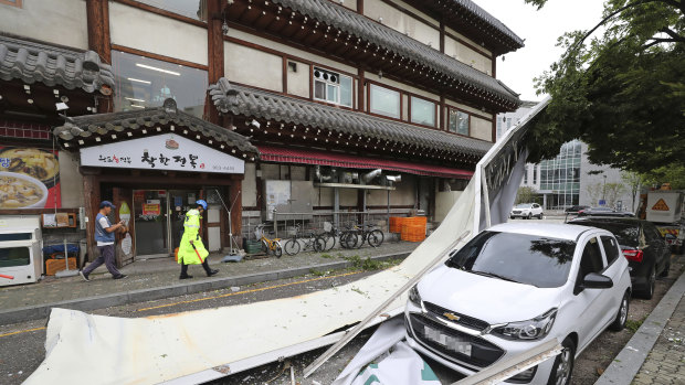 A vehicle is damaged by a fallen sign from a building as Typhoon Lingling brings strong winds and rain to Seoul.