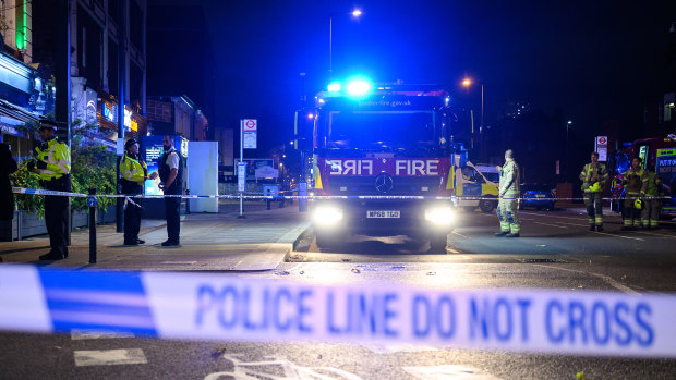 Police officers and fire crews are seen within the cordon around Edmonton Green police station, following an incident involving a car colliding with the front doors of the building.