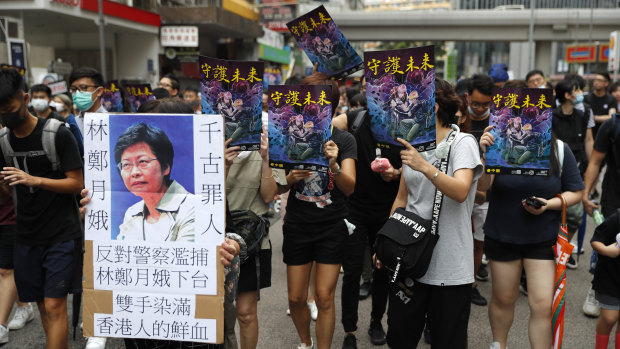 A protester holds a sign that reads: "Carrie Lam condemned by history," as they march through the streets of Mong Kok.