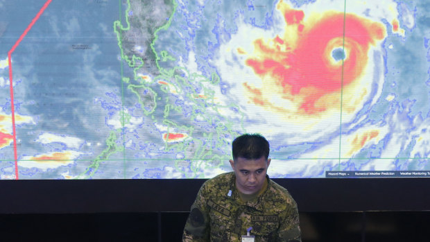 A member of the Philippine Air Force stands in front of a satellite image of Typhoon Mangkhut, locally named Typhoon Ompong, at the National Disaster Risk Reduction and Management Council operations center in Manila.