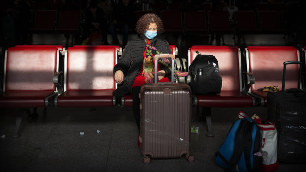 A traveller wears a face mask as she sits in a waiting room at a Beijing railway station. Cases of the virus have been confirmed in Beijing.