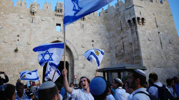Israelis wave national flags outside the Old City's Damascus Gate, in Jerusalem.