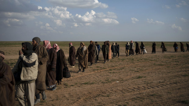 Men walk to be screened by US-backed Syrian Democratic Forces  fighters after being evacuated  near Baghouz, in eastern Syria. The number of people in the area has surpassed earlier estimates.