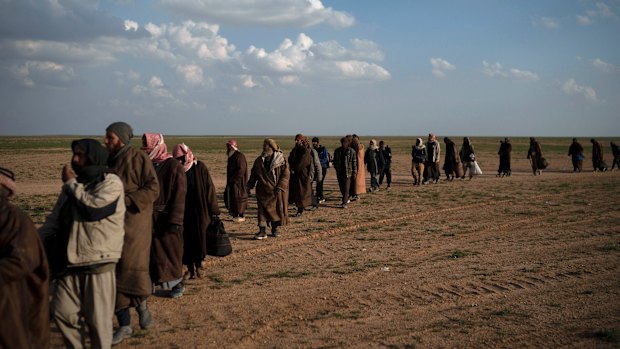 Men walk to be screened by US-backed Syrian Democratic Forces  fighters after being evacuated  near Baghouz, in eastern Syria. The number of people in the area has surpassed earlier estimates.