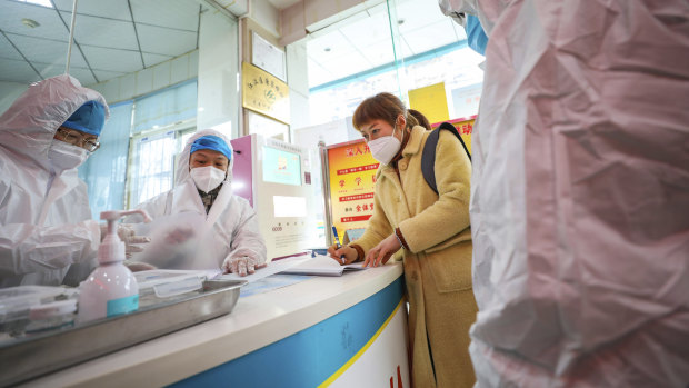 Medical workers in protective gear talk with a woman suspected of being ill with a coronavirus at a community health station in Wuhan in central China's Hubei Province.