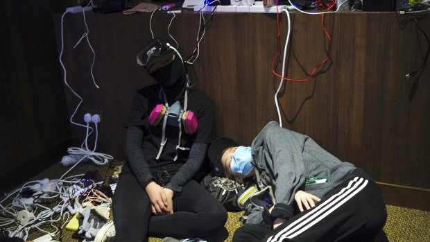 Pro-democracy protesters take a nap while charging their devices inside the campus of the Hong Kong Baptist University in Hong Kong.