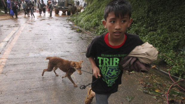 A boy evacuates to safer ground with his pet dog as workers try to clear a landslide that occurred in Itogon township, Benguet province in the northern Philippines.
