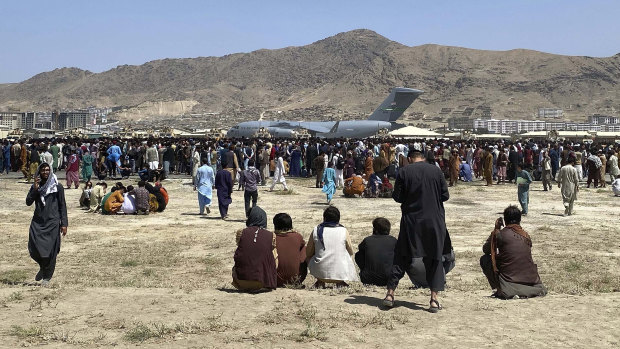 Hundreds of people gather near a US Air Force C-17 transport plane along the perimeter at the international airport in Kabul, Afghanistan. 