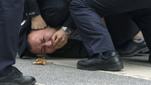 Police pin down a protester on a street in Shanghai on Sunday.