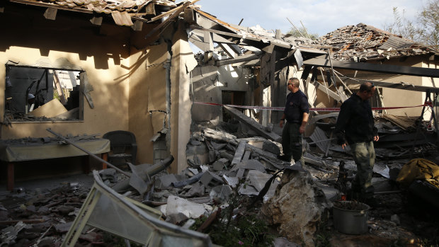 Police officers inspect the damage to a house hit by a rocket in Mishmeret, central Israel, on Monday.