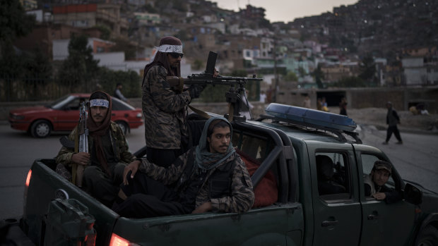Taliban fighters sit on the back of a pickup truck as they stop on a hillside in Kabul.