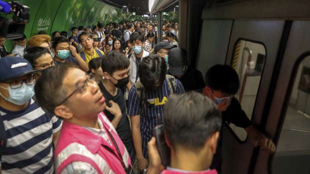 Protesters snarl the morning rush by blocking train doors at Fortress Hill MTR station in Hong Kong on Monday.