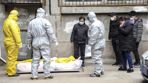 Funeral home workers remove the body of a person suspected to have died from the coronavirus outbreak from a residential building in Wuhan in February.