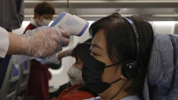 Stewardesses take temperatures of passengers as a preventive measure for the coronavirus on an Air China flight from Melbourne to Beijing.