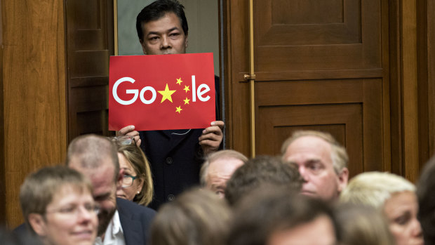 A man holds up a sign of an altered Google logo during a House Judiciary Committee hearing with Sundar Pichai, Google CEO, in Washington on Tuesday.