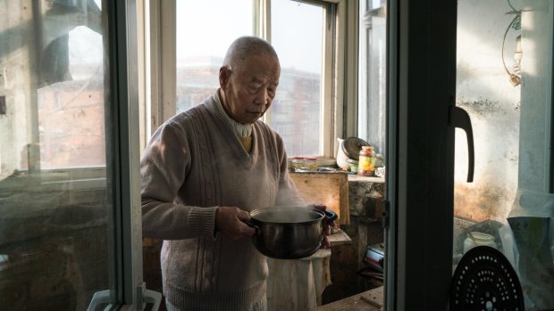 Han holds part of his breakfast, a pot of boiled soy milk, in his kitchen. 
