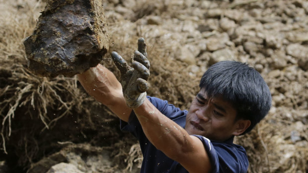 A gold miner moves a stone while searching for victims believed to have been buried by a landslide after typhoon Mangkhut barrelled across Itogon, Benguet province, northern Philippines on Monday.