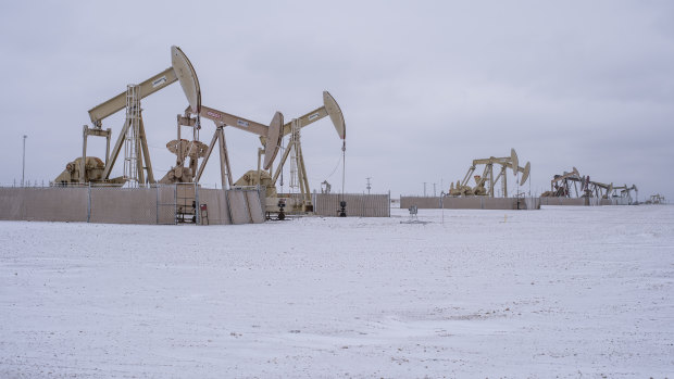 Pump jacks operate in the Permian Basin in Midland, Texas, covered by snow.
