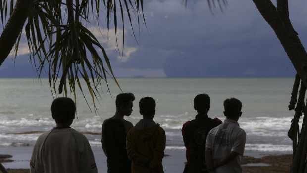 People watch as Mount Krakatau, left, and Anak Krakatau, right, are seen off the coast of Carita beach, Indonesia, this week.