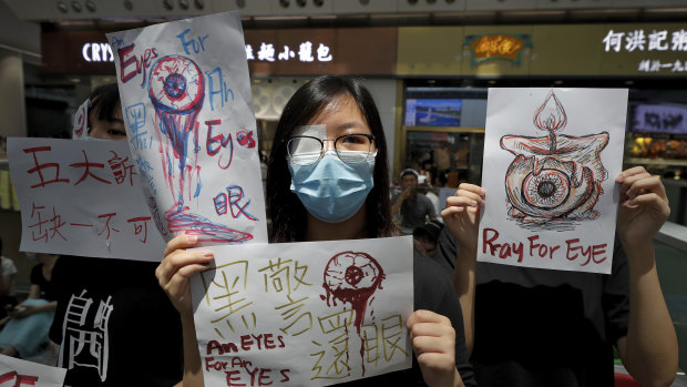 People hold signs which read "Black Police, Return eye," bottom centre, during the protest at the airport's arrival hall.