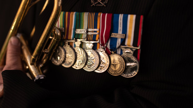 Afghanistan war veteran Duncan Clements displays his medals as he plays the bugle at  Parkes War Memorial.