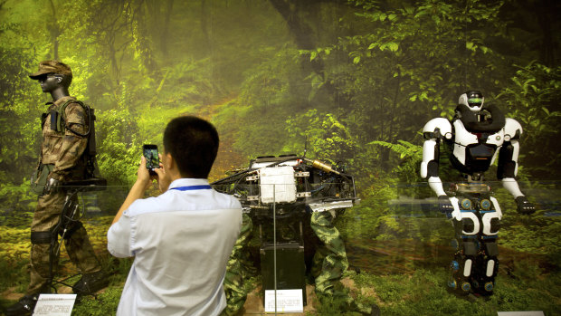A visitor takes a photo of a display of robotic military technology at an exhibition highlighting China's achievements under five years of leadership by Chinese President Xi Jinping.