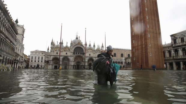 A woman carries her daughter in a flooded St Mark's Square in Venice on Tuesday.