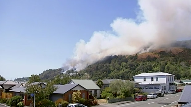 Smoke rises from a busfire coming over the ridge behind a residential area in Wakefield, New Zealand, on Friday. 