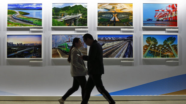 People walk by a display board showcasing China's construction projects at the media centre of the Belt and Road Forum in Beijing.