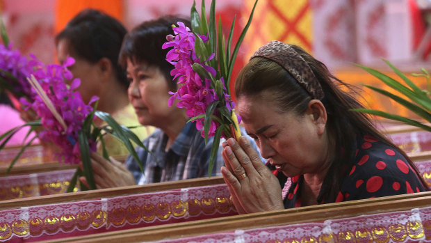 Worshippers pray as they take turns sitting in coffins at the Takien temple in Thailand.
