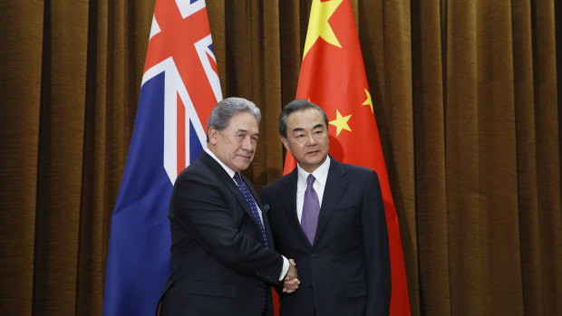 Which flag is that? NZ acting PM Winston Peters, left, shakes hands with Chinese Foreign Minister Wang Yi. 