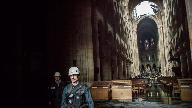 A man walks inside the damaged Notre-Dame Cathedral on Tuesday.