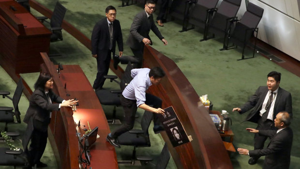 Politician Au Nok-hin leaps across desks to chase Carrie Lam in the Legislative Council in Hong Kong on Thursday.