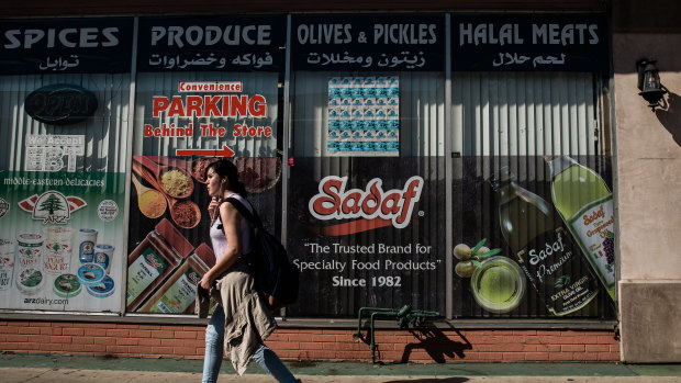 A young woman passes by a Middle Eastern market on Main Street in El Cajon, California. 