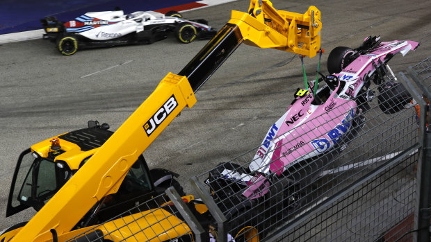 Bad books: A crane lifts Esteban Ocon's damaged Force India from the track after he crashed with teammate Sergio Perez.