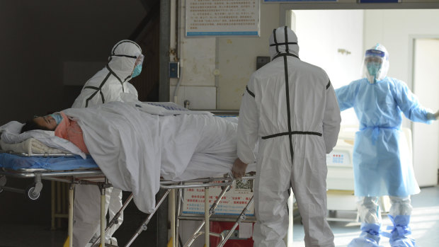 Medical workers in protective suits move a coronavirus patient into an isolation ward at the Second People's Hospital in Fuyang in central China's Anhui Province.
