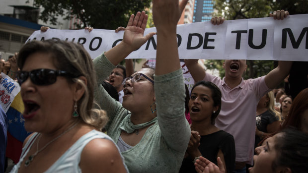 Demonstrators hold signs and shout slogans during a protest against Nicolas Maduro in Caracas on Wednesday.