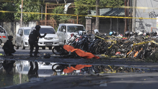 Members of a police bomb squad inspect the wreckage of motorcycles at the site where an explosion went off outside a church in Surabaya, East Java.