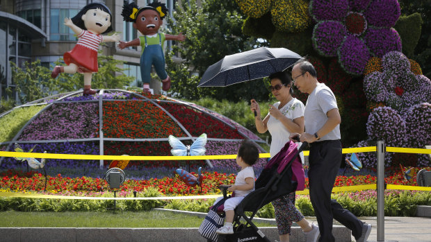 A couple and a child walk by a decoration titled "Common Prosperity" set up for the Forum on China-Africa Cooperation in Beijing.