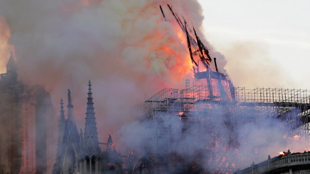 The spire collapses as flames burn the roof of the Notre-Dame Cathedral.