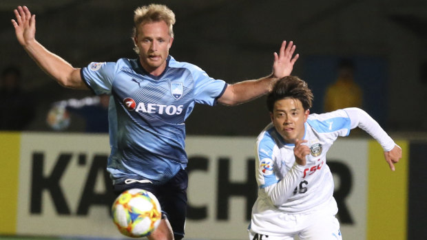 Sydney FC defender Ryan Grant (EFT) competes with Frontale's Tatusya Hasegawa.