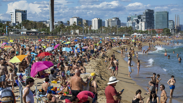 People enjoy the warm weather on the beach in Barcelona. Spanish government has announced that the north-western region of Galicia will move next week to what the government calls "the new normal".