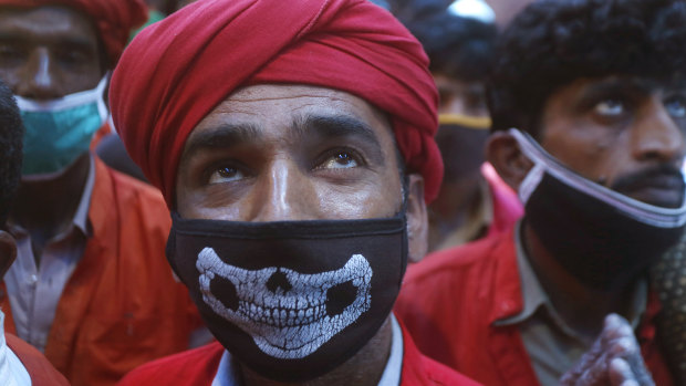 A daily-wage worker waits with others to receive relief food supplies in Lahore, Pakistan.