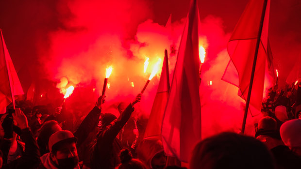 People hold red flares and Polish National flag during the Independence day march organized by ultra-Catholic right-wing groups on the 102nd Anniversary of Poland's independence day in Warsaw, Poland. 